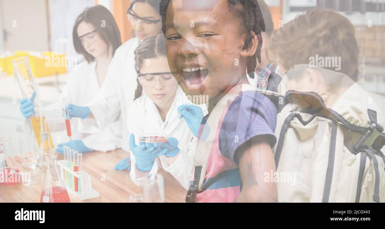 Estudiante afroamericano con boca abierta y estudiantes multirraciales haciendo experimentos en laboratorio Foto de stock