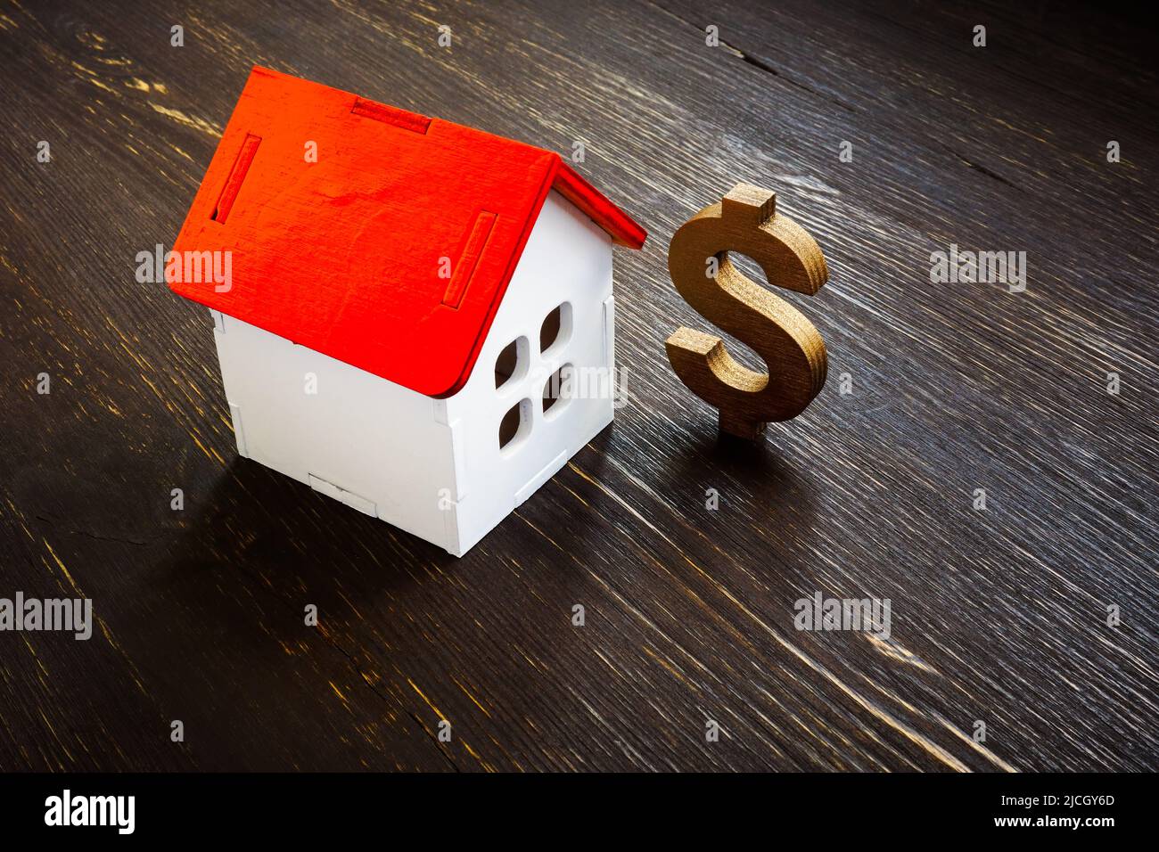 Modelo de casa y signo de dólar en la mesa. Valor inmobiliario. Foto de stock