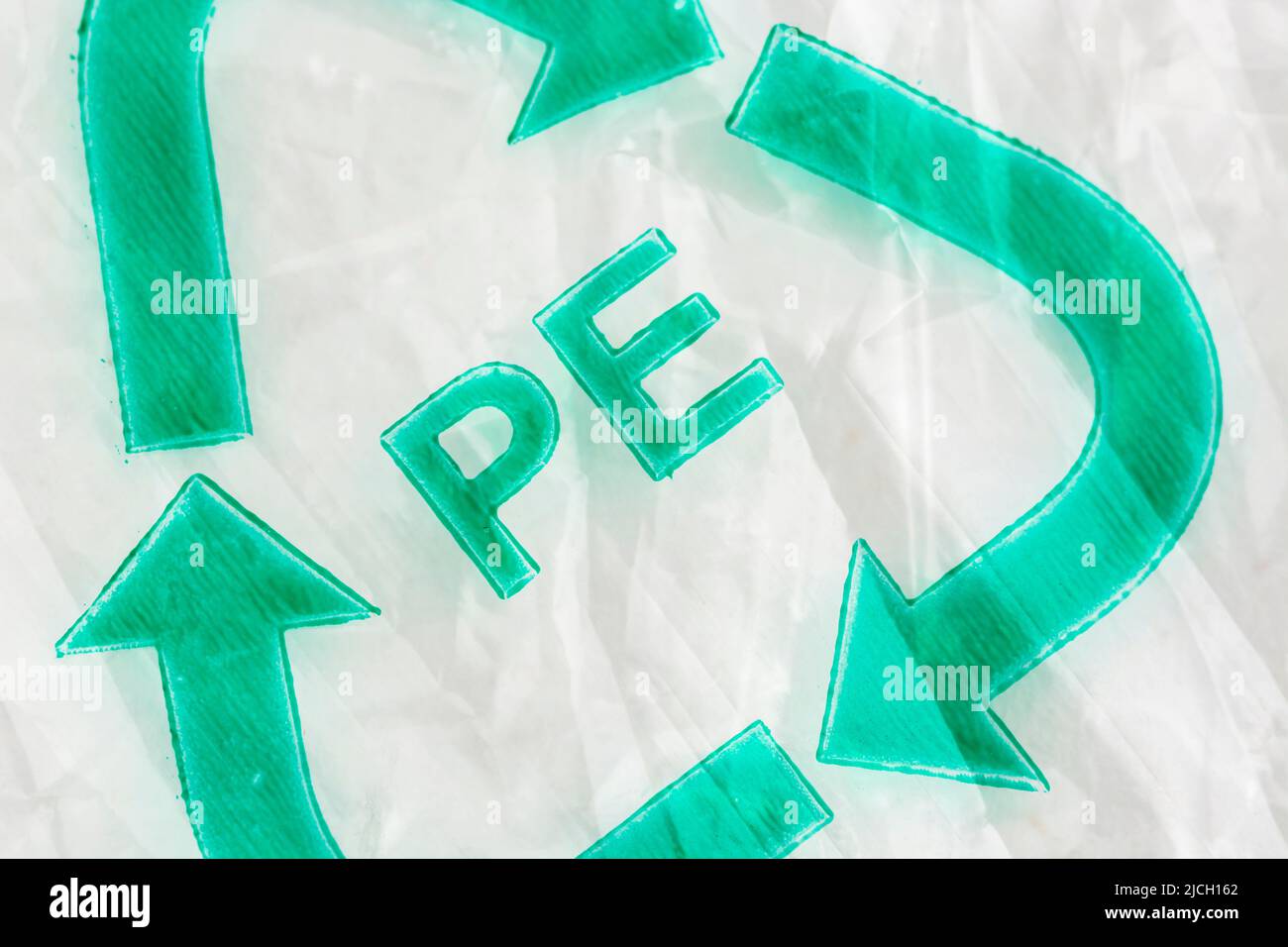 Logotipo de reciclaje Mobius impreso en verde sobre bolsa de plástico arrugada con letras PE para polietileno. No está claro si se trata de una clasificación 'antigua' o no oficial. Foto de stock
