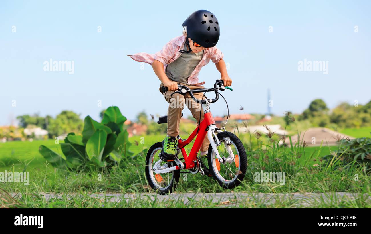 Un niño de tres años, con un casco de bicicleta y gafas de sol en su  bicicleta Fotografía de stock - Alamy