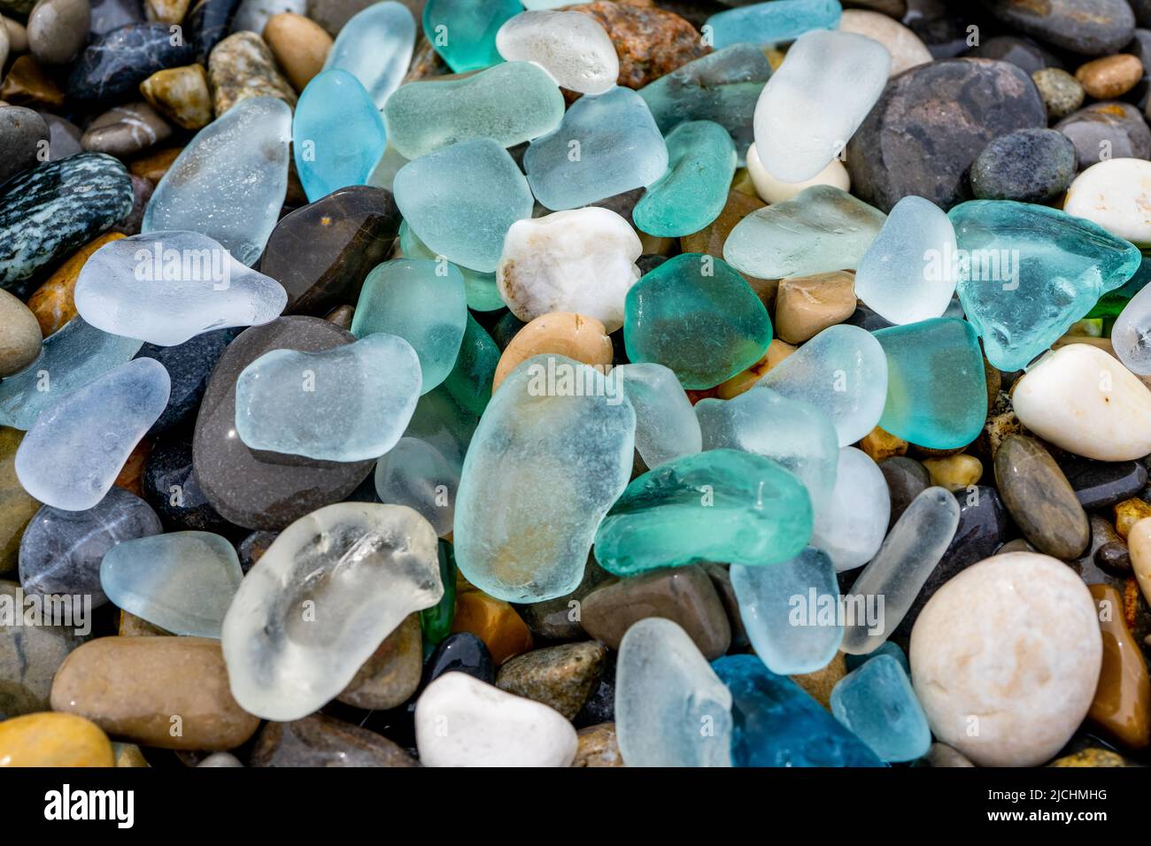 Cristal de mar natural pulido y piedras en la orilla del mar. Azul agua  clara de mar con olas. Vidrio verde, azul brillante con guijarros de mar  multicolor Fotografía de stock -
