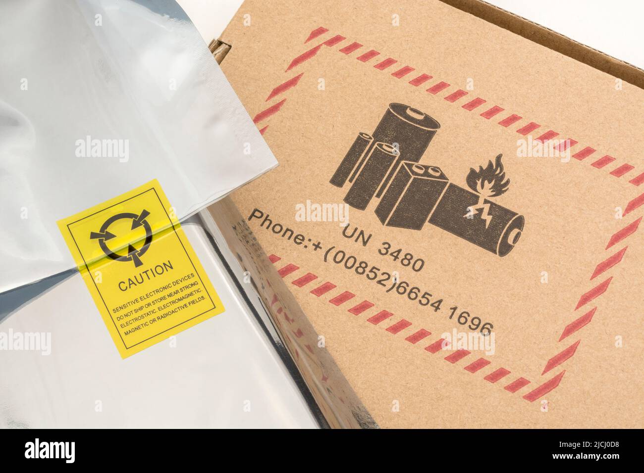 Bolsa de plástico plateada antiestática con un símbolo de advertencia antiestático y embalaje de cartón con un símbolo de advertencia de peligro de batería UN 3480. Foto de stock