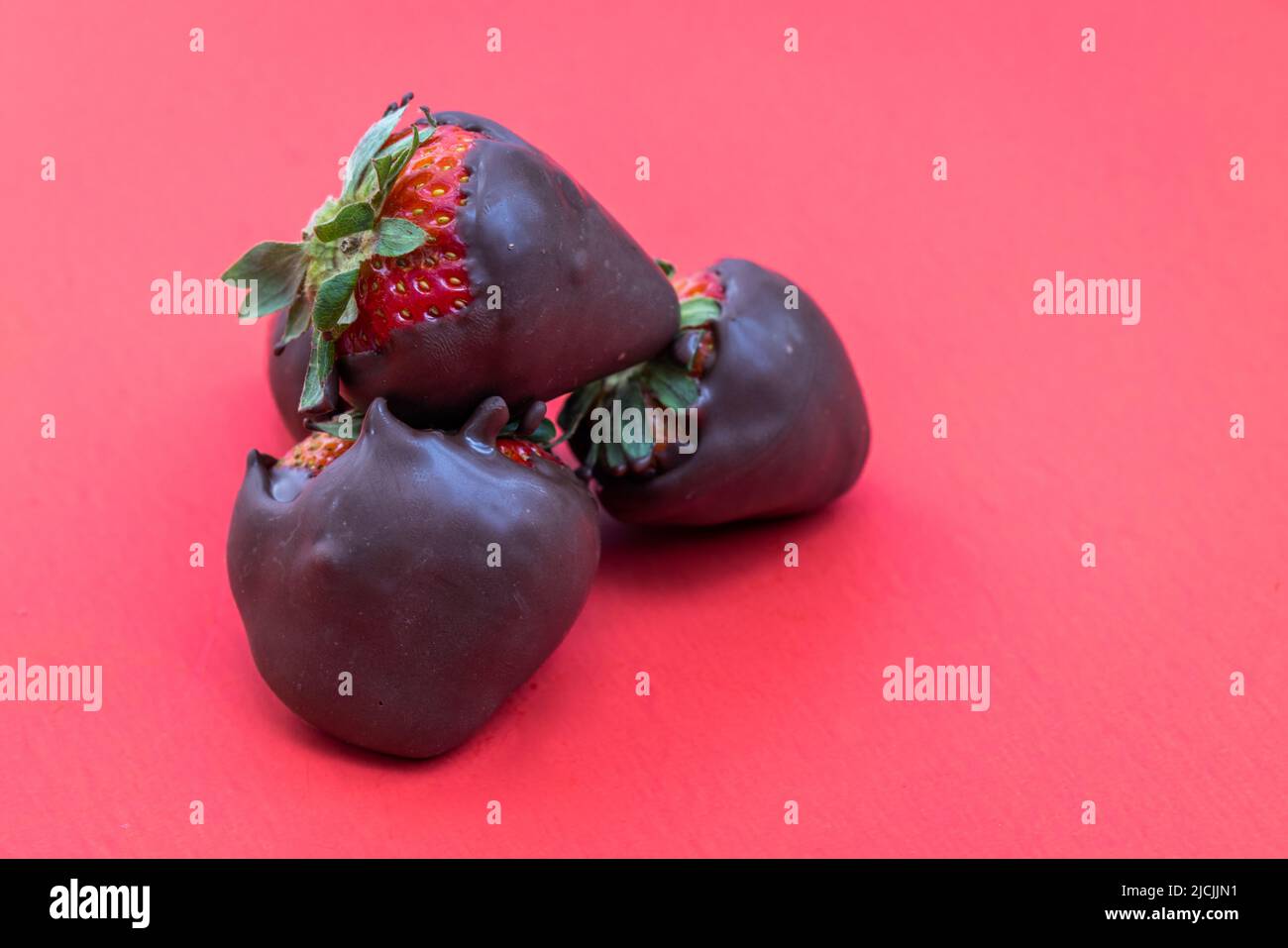 fresas cubiertas de chocolate aisladas sobre fondo rojo Foto de stock