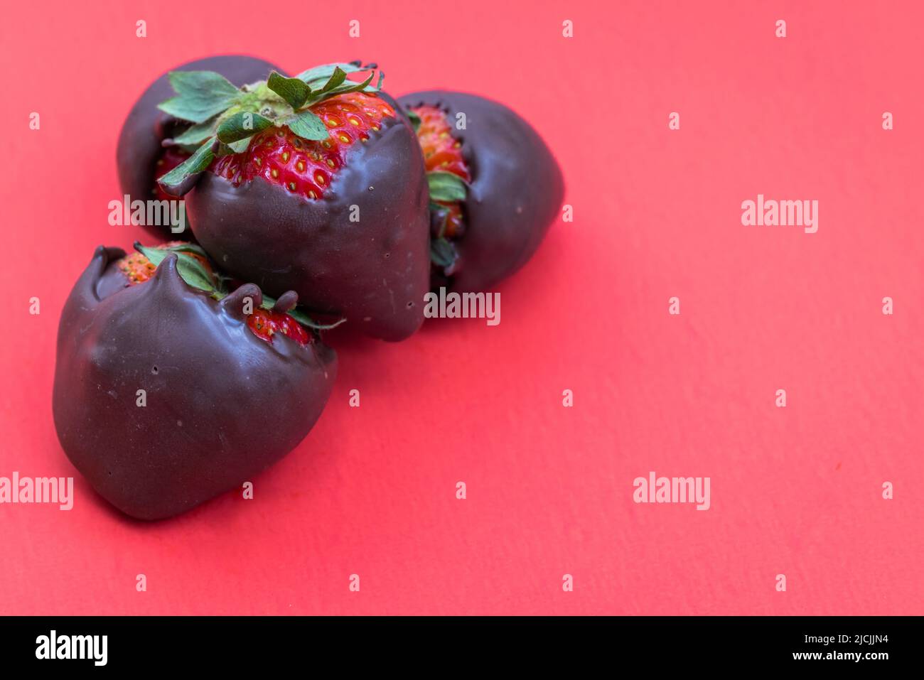 fresas cubiertas de chocolate aisladas sobre fondo rojo Foto de stock