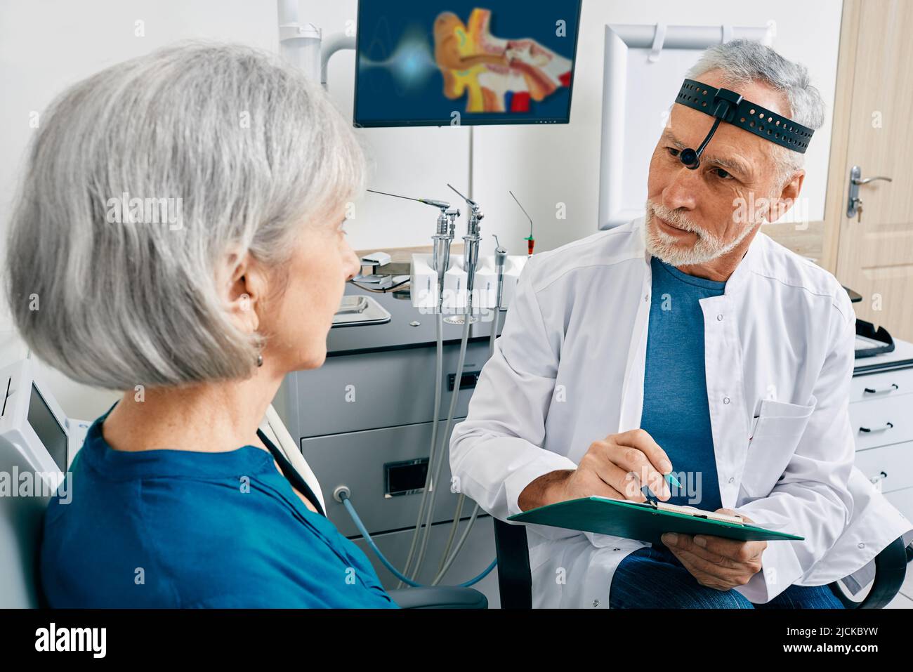 Médico de pelo gris que hace la consulta para la paciente mayor con problemas de salud en el centro de ENT. Consulta con el médico de ENT Foto de stock