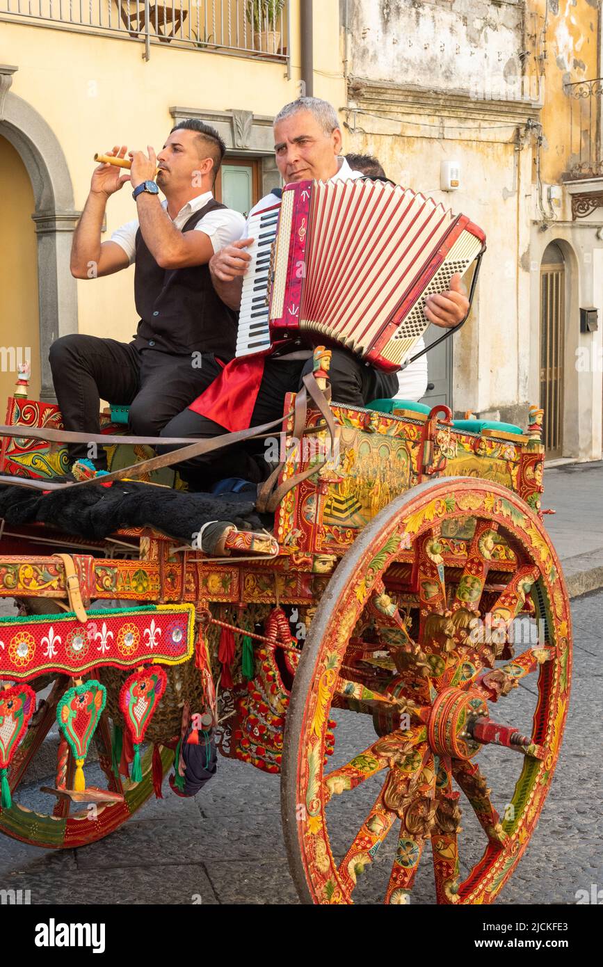 Músicos folclóricos tradicionales sicilianos con su caballo y carro elegantemente decorados, en el festival anual de fresas en Maletto, Sicilia, Italia Foto de stock