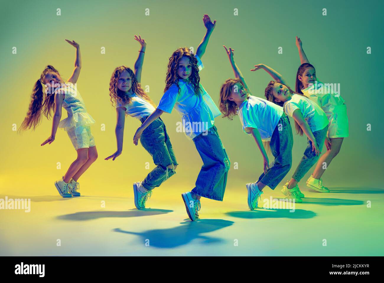 Grupo de niños, niñas en ropa deportiva de estilo informal bailando en  clase de coreografía aisladas sobre fondo verde en luz amarilla de neón  Fotografía de stock - Alamy
