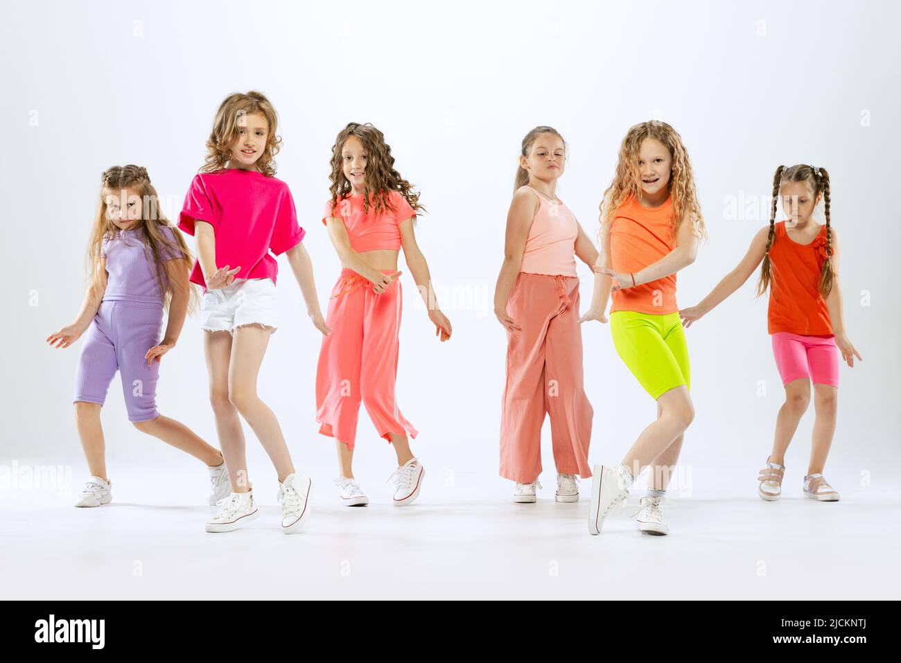 Niñas pequeñas y deportivas, niños con ropa de colores brillantes bailando danza moderna aislada sobre fondo blanco estudio. Concepto de música, moda, arte Fotografía de stock Alamy