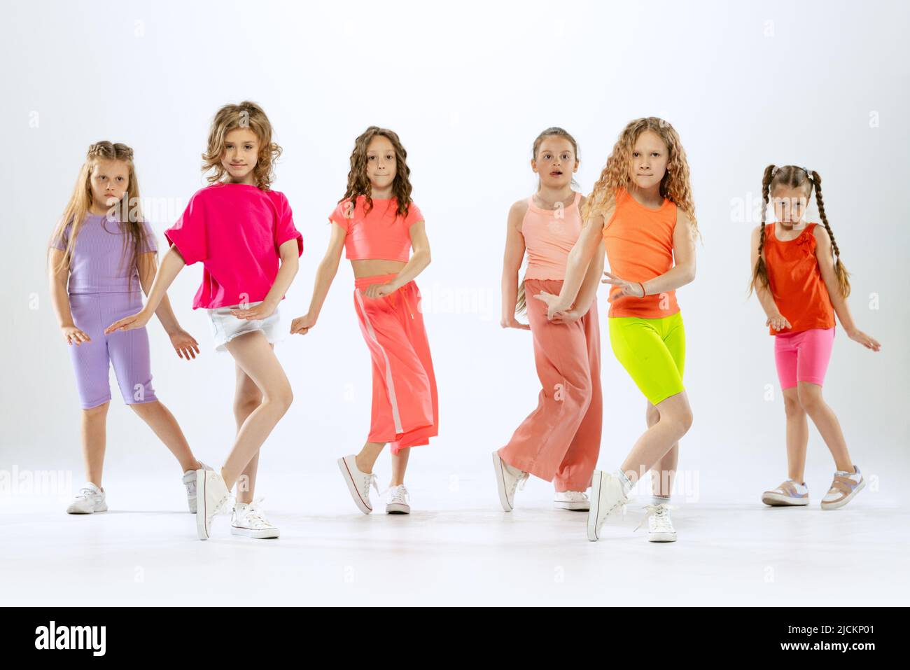 Niñas pequeñas y deportivas, niños con ropa de colores brillantes bailando danza moderna aislada sobre fondo blanco estudio. Concepto de música, moda, arte Fotografía de stock Alamy