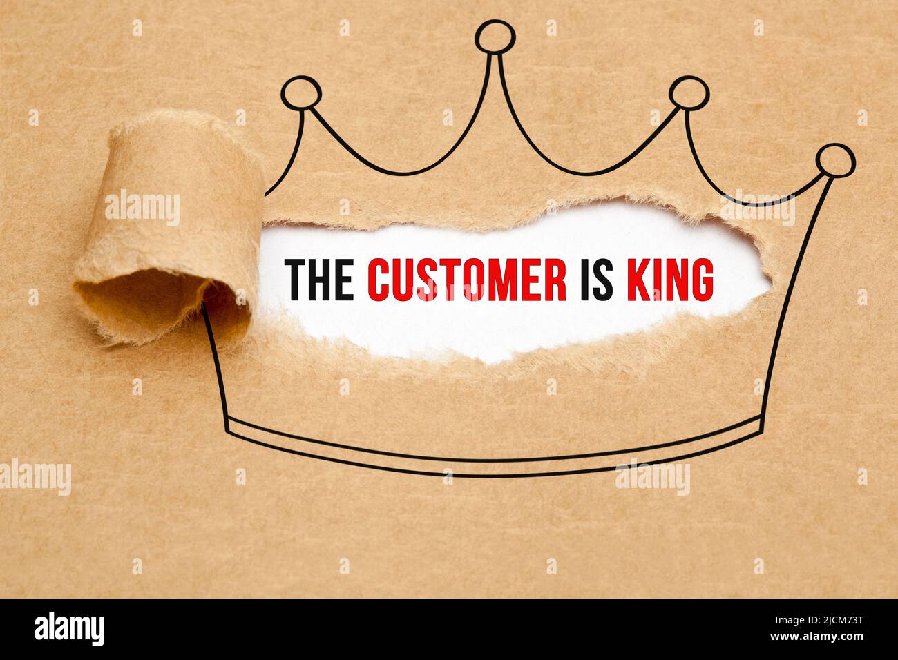 Eslogan El cliente es el rey que aparece detrás de papel marrón rasgado. Concepto de negocio de satisfacción del cliente. Foto de stock