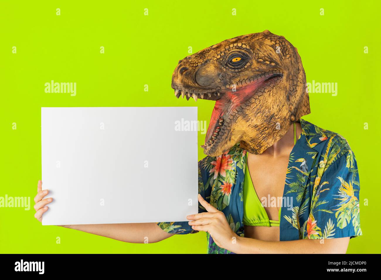 Mujer divertida usando una máscara animal de dinosaurio sosteniendo un  cartón blanco vacío aislado sobre fondo verde del estudio Fotografía de  stock - Alamy