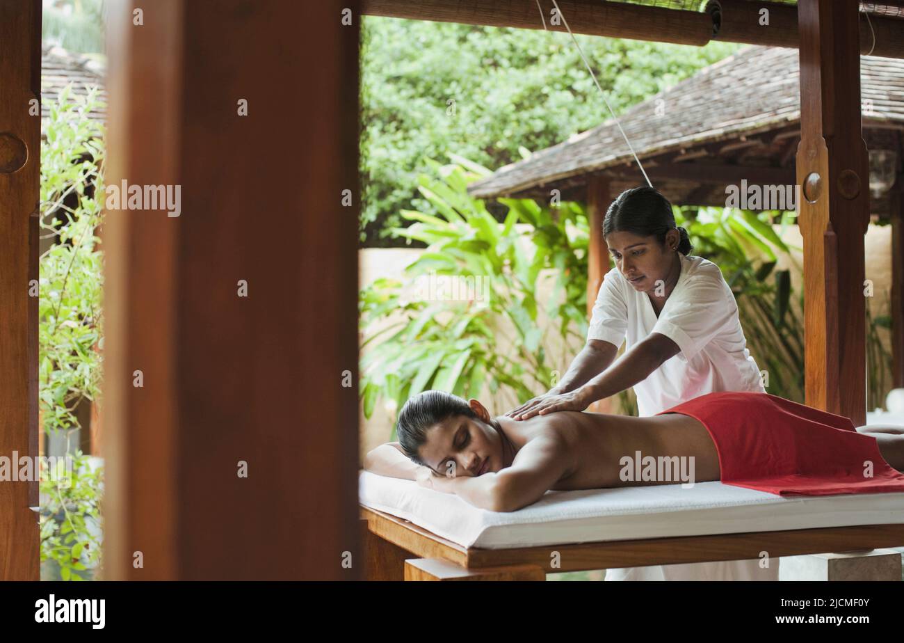 Mujer recibiendo masaje de tejidos profundos. Este tratamiento de masaje en el spa Sahanah, Saman Villas, se centra en las capas más profundas de tejidos musculares y objetivos Foto de stock