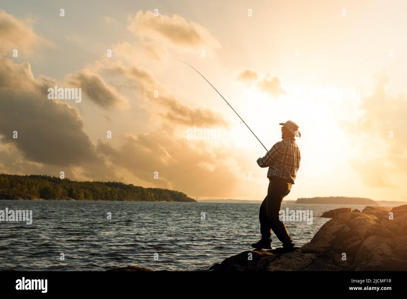 pesca en el banco. pescador con caña giratoria al atardecer. espacio de copia Foto de stock