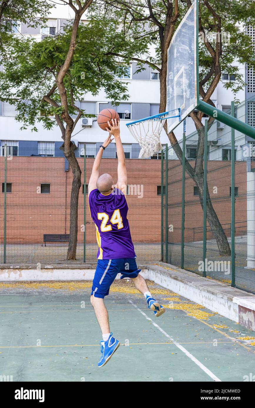 Un joven jugador de baloncesto rodando una pelota de baloncesto Foto de stock