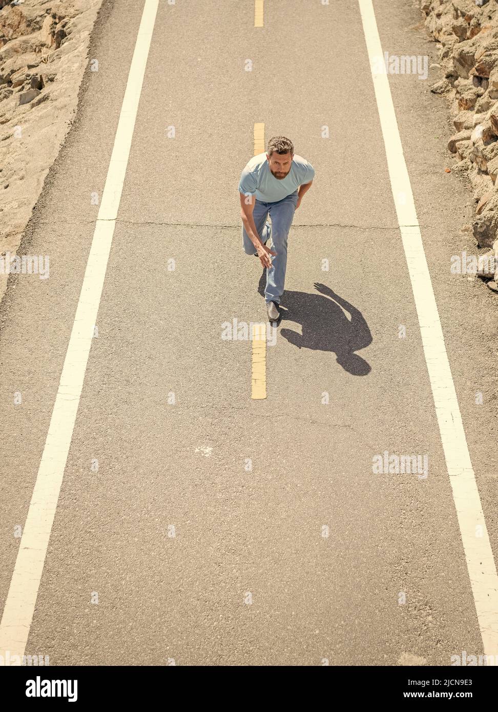 hombre atlético maduro corriendo en carretera al aire libre, enérgico Foto de stock