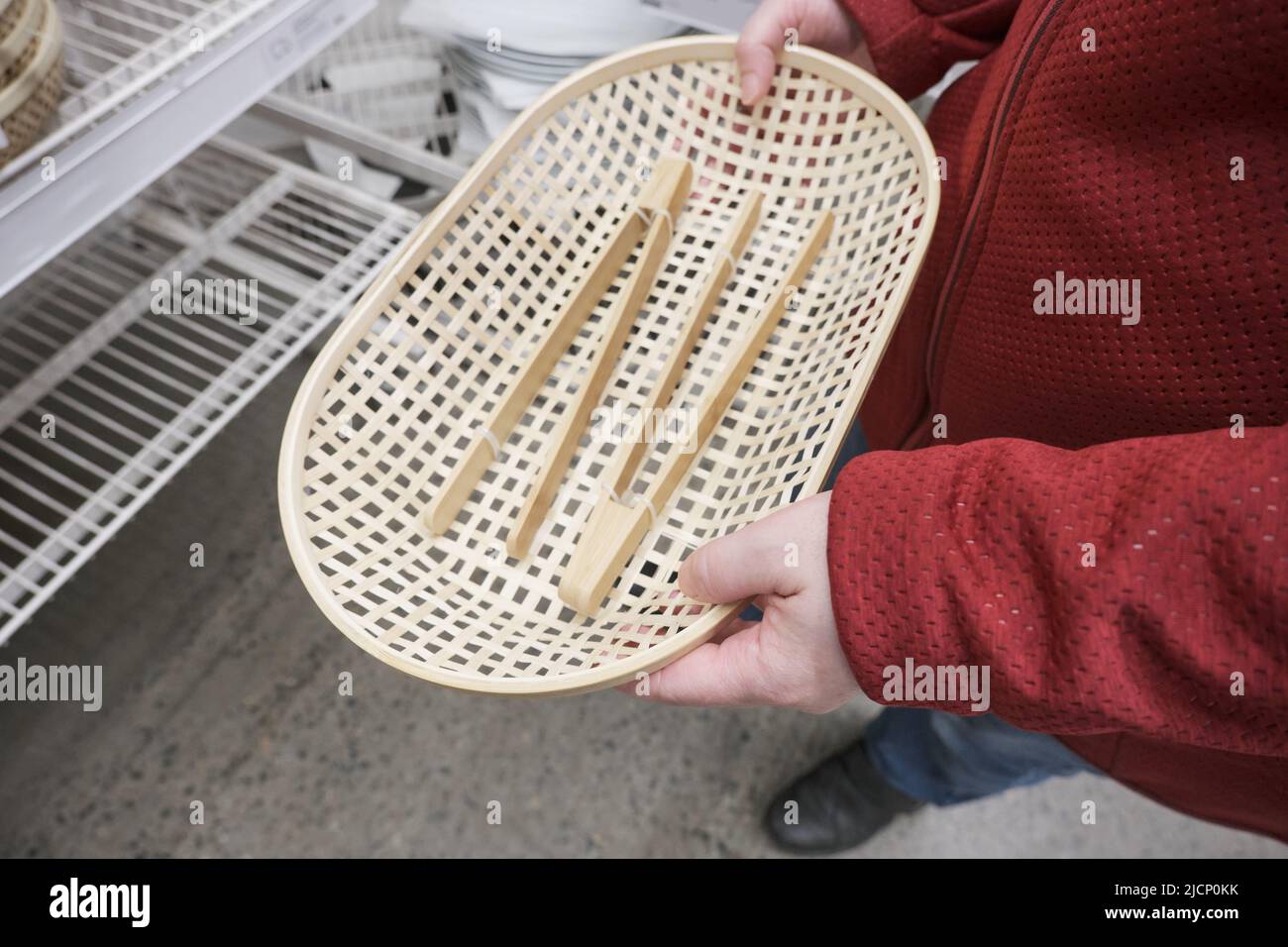 La chica caucásica compra platos de madera, pan de mimbre con pinzas de madera en una tienda Foto de stock
