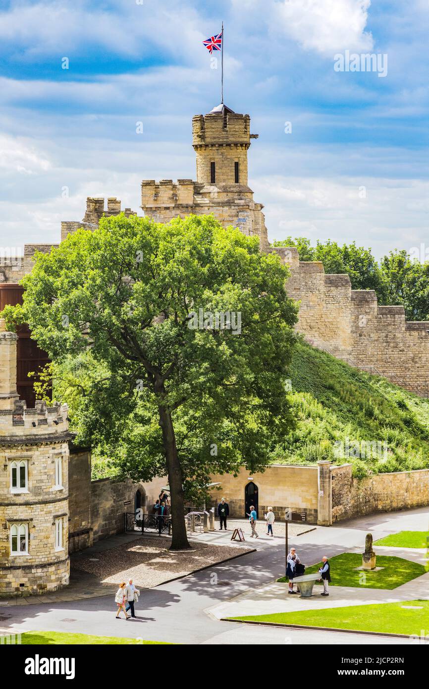 27 de julio de 2019: Lincoln, Reino Unido - El terreno del castillo, con turistas de turismo y un hermoso árbol en plena hoja de verano. Foto de stock