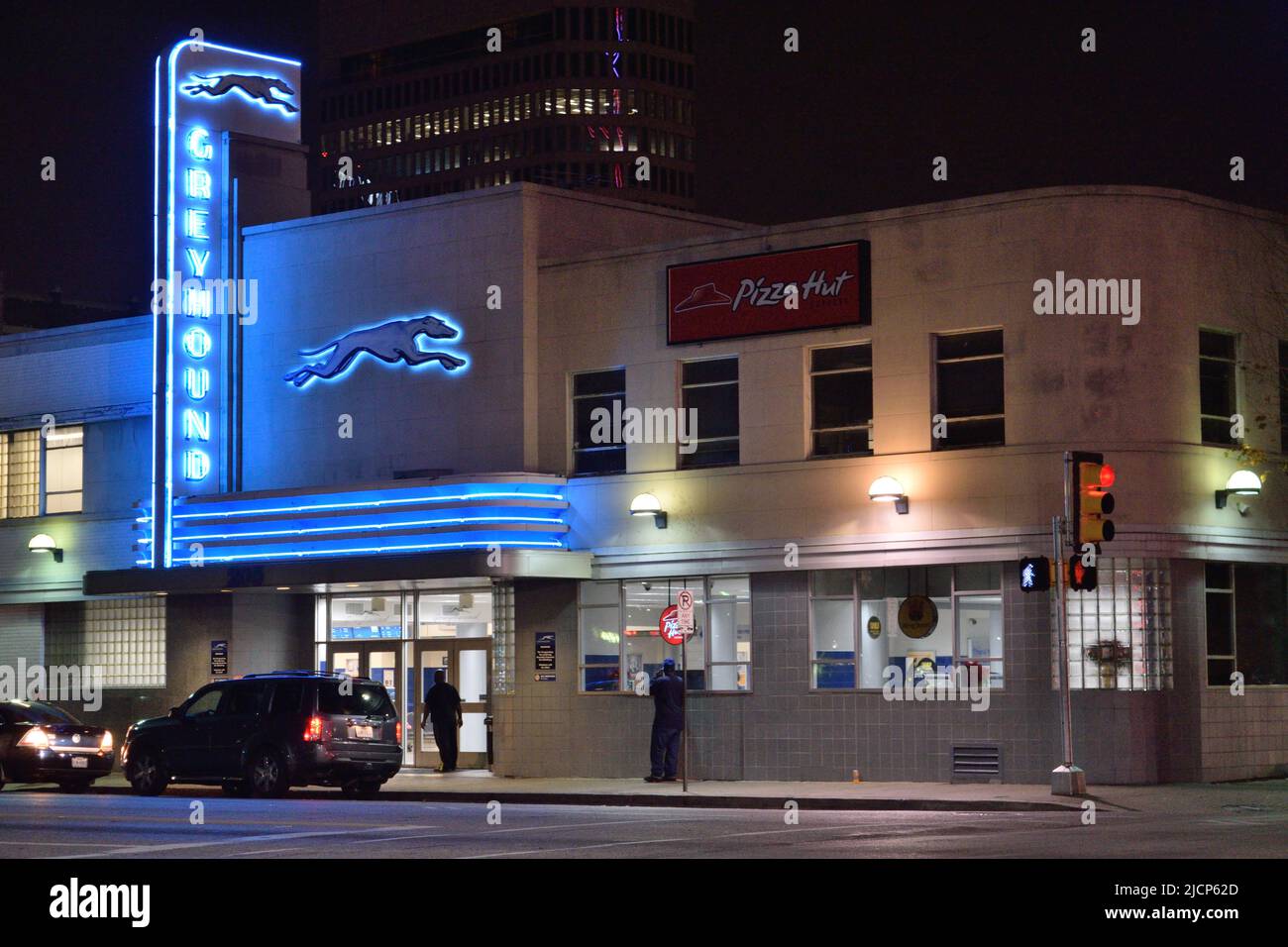 Coches estacionados frente a la estación de autobuses Greyhound, con luces de neón azules, en el centro de Dallas, Texas ca. 2015 Foto de stock