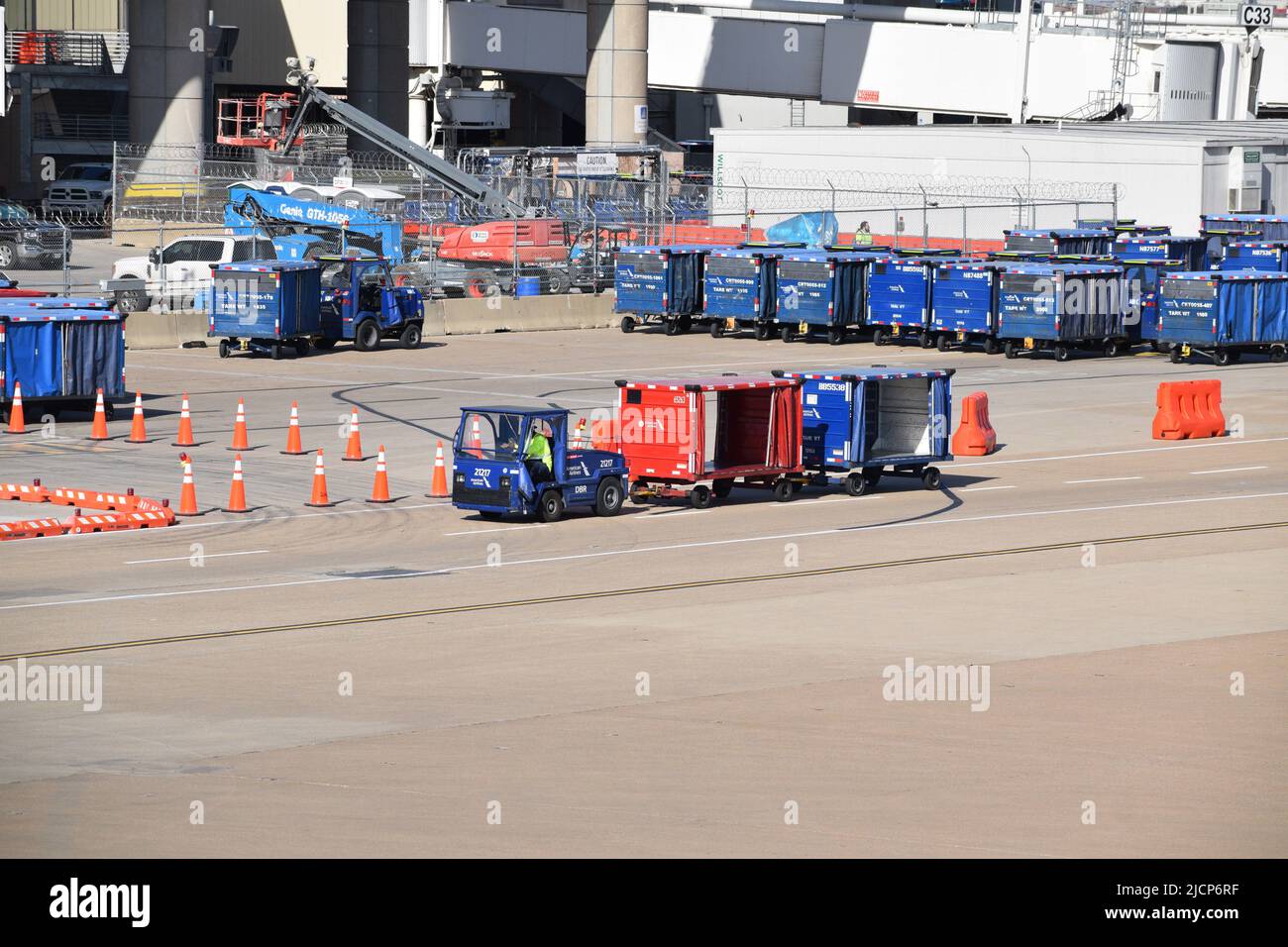 Una rampa de American Airlines presta servicios a un trabajador que conduce un tractor tirando de carros de equipaje fuera de la Terminal C en el Aeropuerto DFW (Aeropuerto Dallas-Fort Worth) Foto de stock