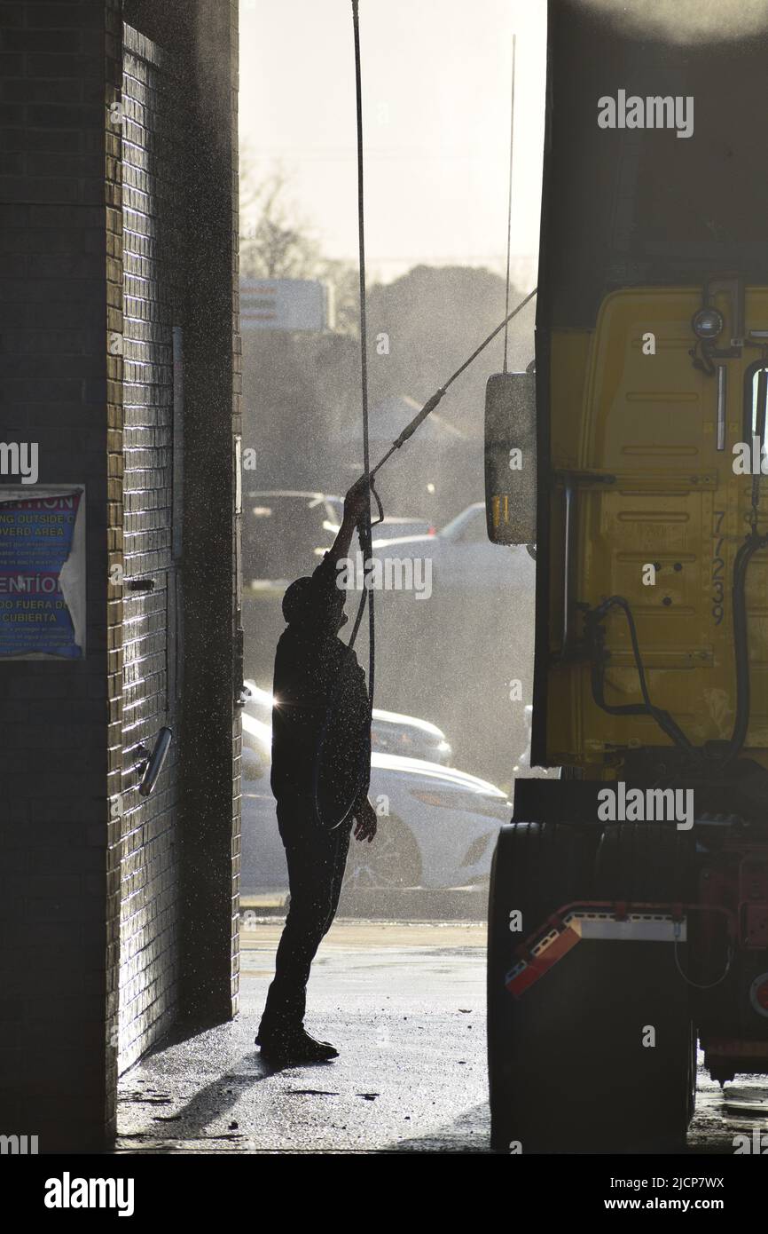 Hombre lavando una cabina de semi-camión a primera hora de la mañana en un lavado de camiones en Irving, Texas Foto de stock