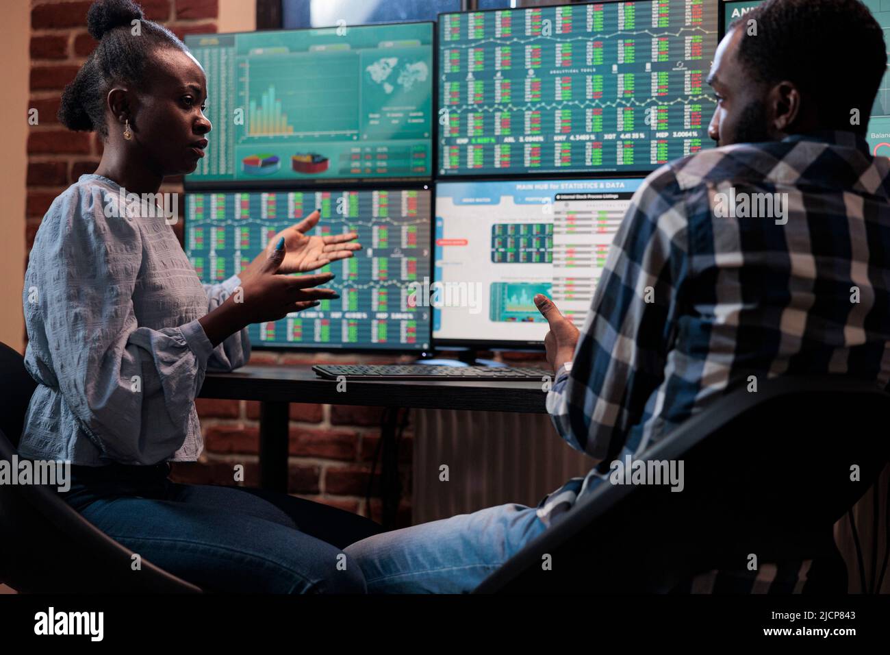 Los comerciantes profesionales de la compañía de inversión que se sientan  en la estación de trabajo multi monitor mientras analizan los datos  financieros en tiempo real. Los inversionistas de la bolsa de