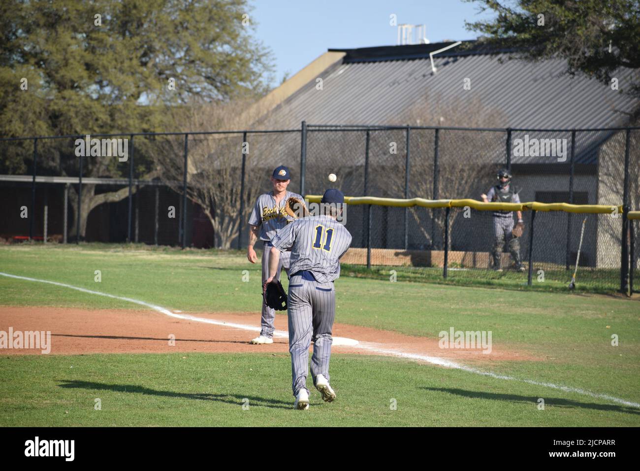 Un lanzador de Ecclesia College lanzando una bola de tierra suave, él se puso en el campo, a los primeros hombres de base durante un juego de béisbol de la universidad Foto de stock