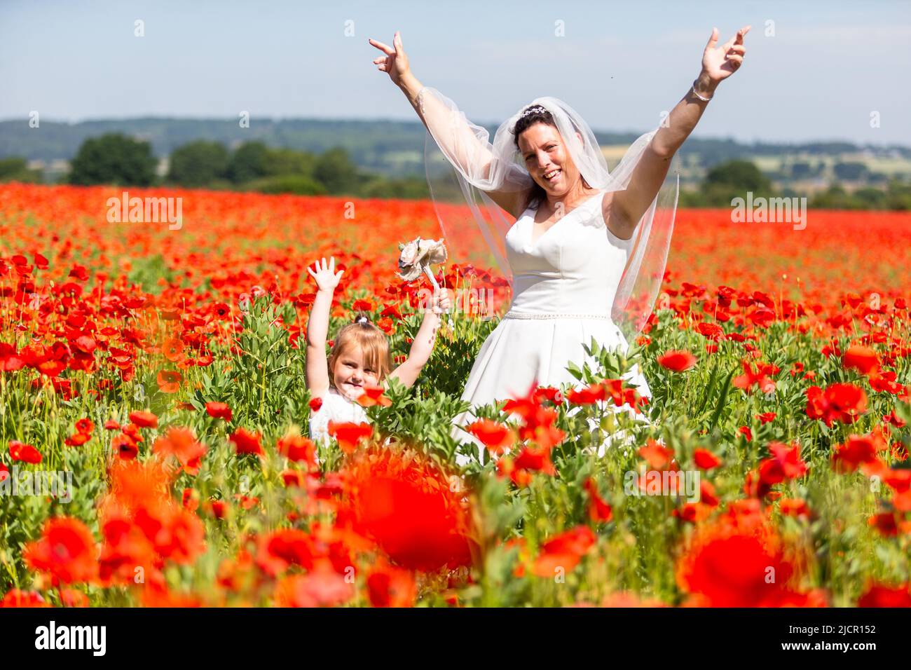 Novia en vestido blanco de la boda en un campo de la amapola, Reino Unido 2022 Foto de stock