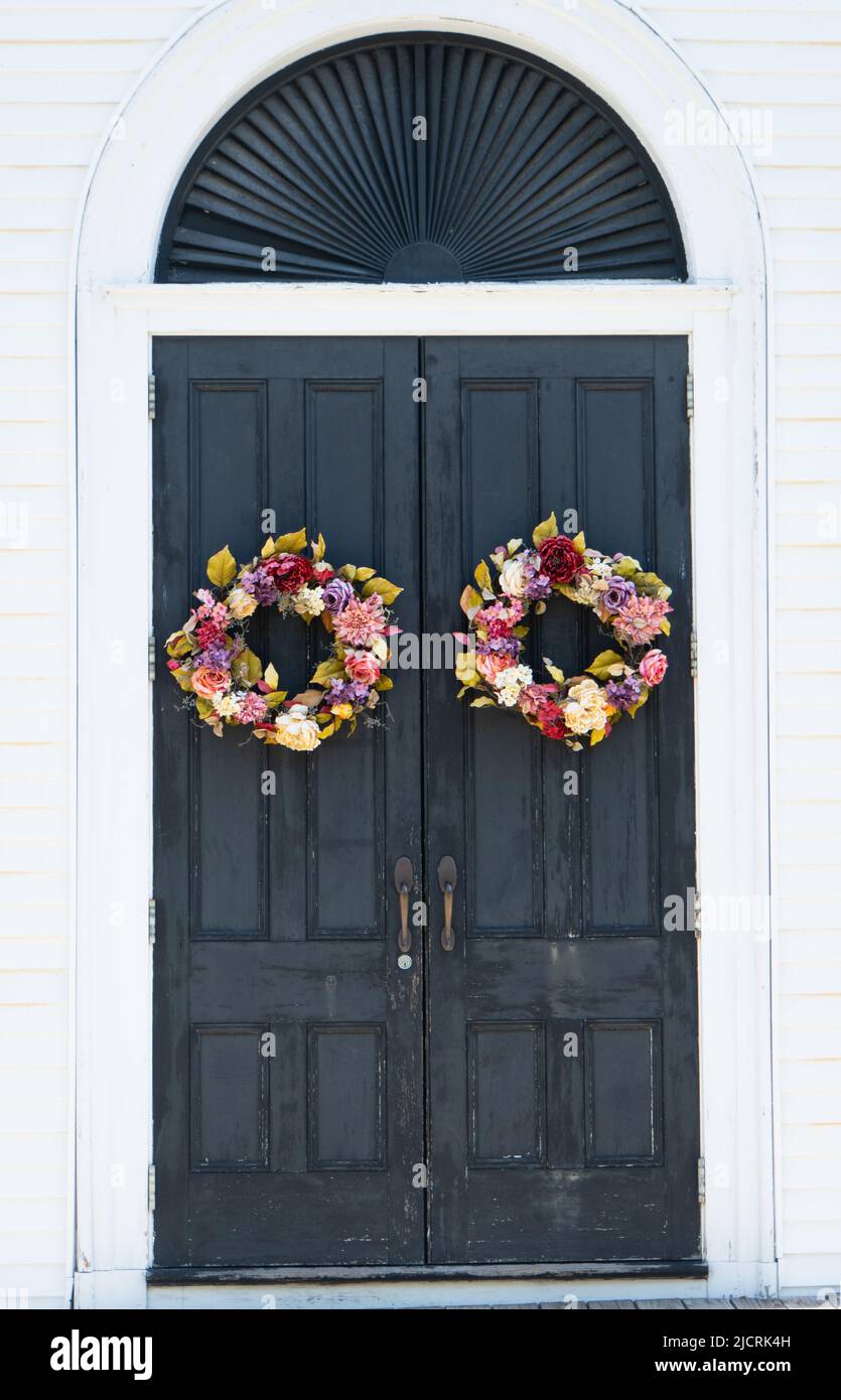 dos coronas de flores decoran las puertas de la iglesia del pueblo Foto de stock