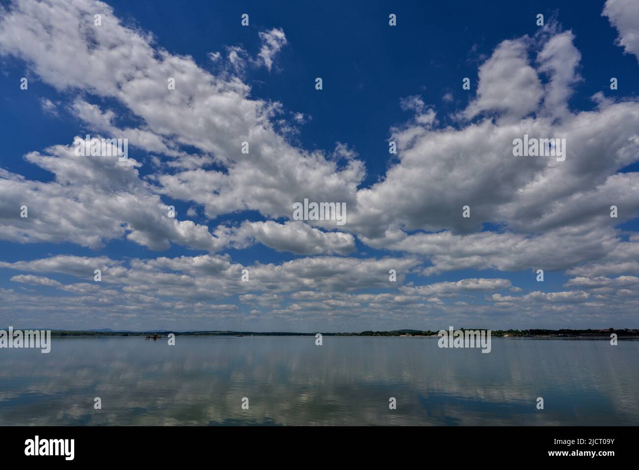Cielo azul con nubes blancas que se reflejan en el agua Foto de stock