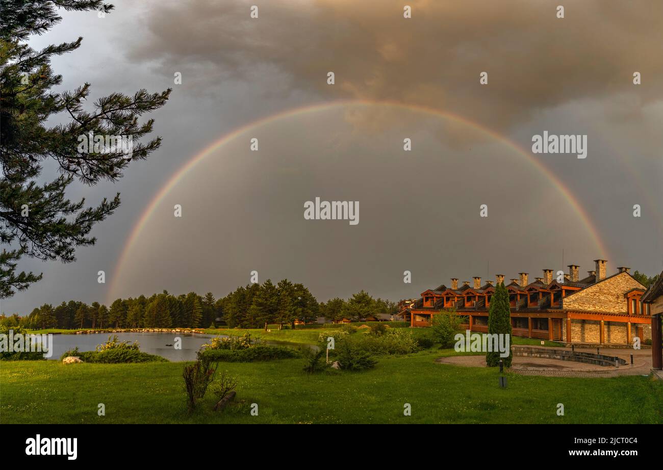 arco iris después de la lluvia con césped verde de golf y lago Foto de stock