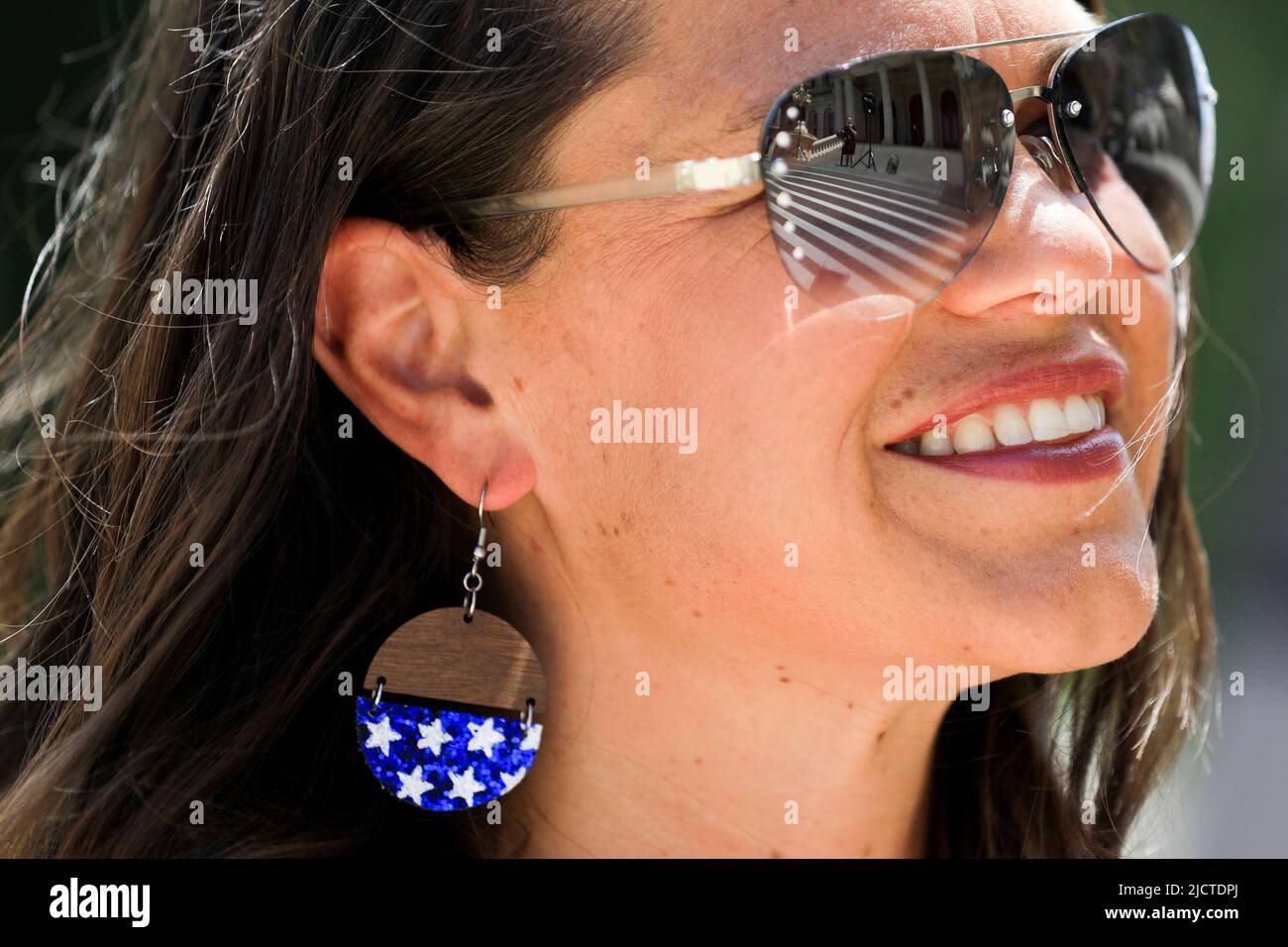 Rachel Atwood, del Condado de Ottawa, sonríe como hablante y se refleja en sus gafas de sol durante un evento de Marcha por la Libertad Médica organizado por Informed Choice Michigan en Lansing, Michigan, EE.UU., 15 de junio de 2022. REUTERS/Emily Elconin Foto de stock