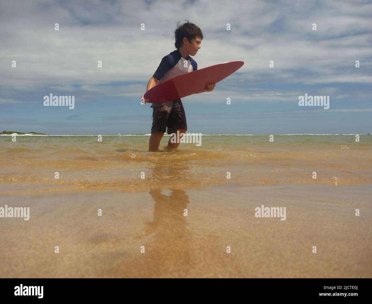 niño con mesa de surf en la playa Foto de stock