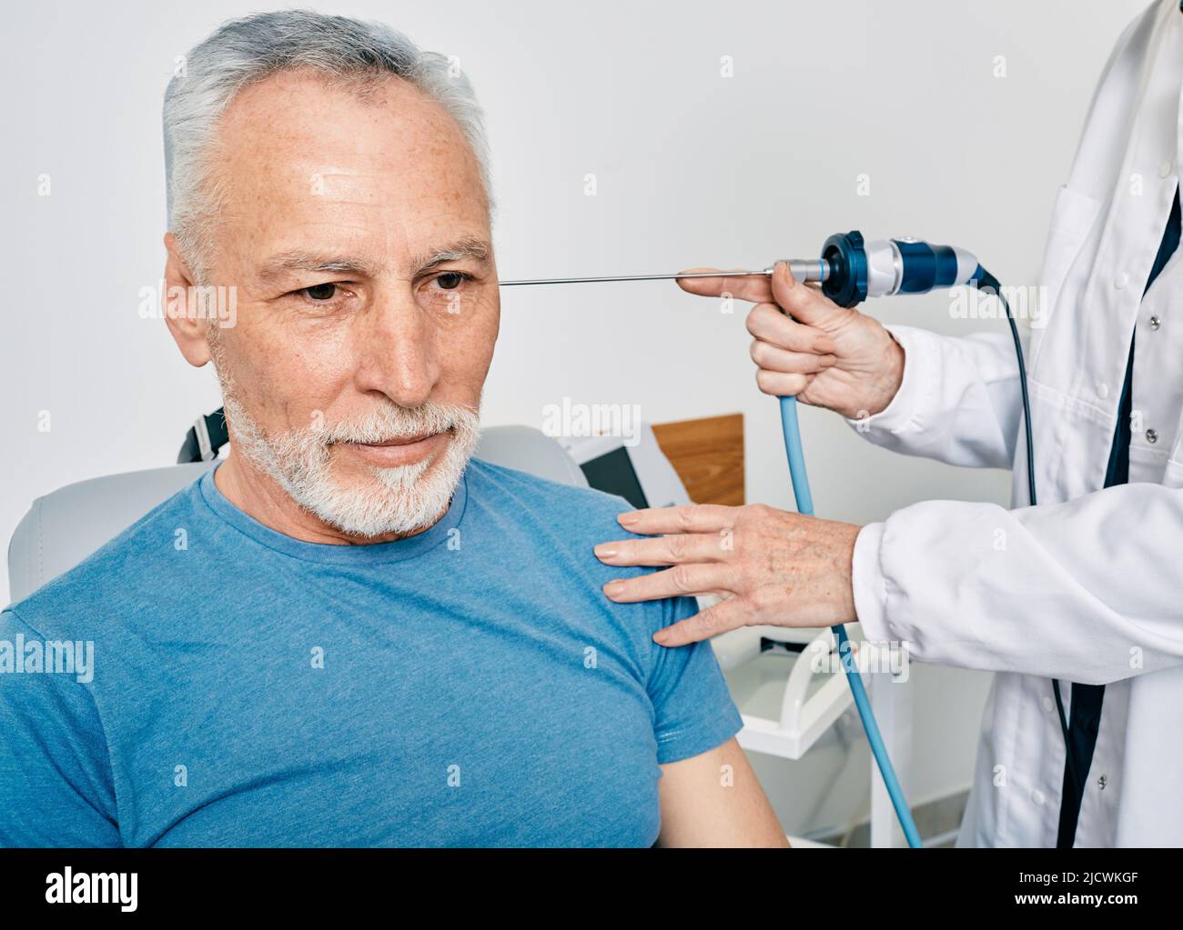Hombre de edad que recibe un examen de oído en la clínica de ENT con otorrinolaringólogo usando un endoscopio de vídeo. Endoscopia del oído Foto de stock