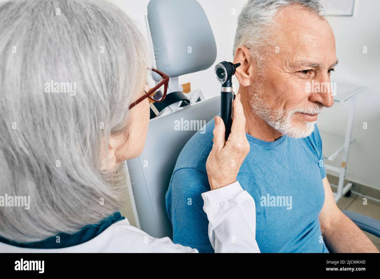 Médico otorrinolaringólogo que revisa el oído del hombre mayor usando un otoscopio o un auriscopio en el centro de audición. Audiología Foto de stock