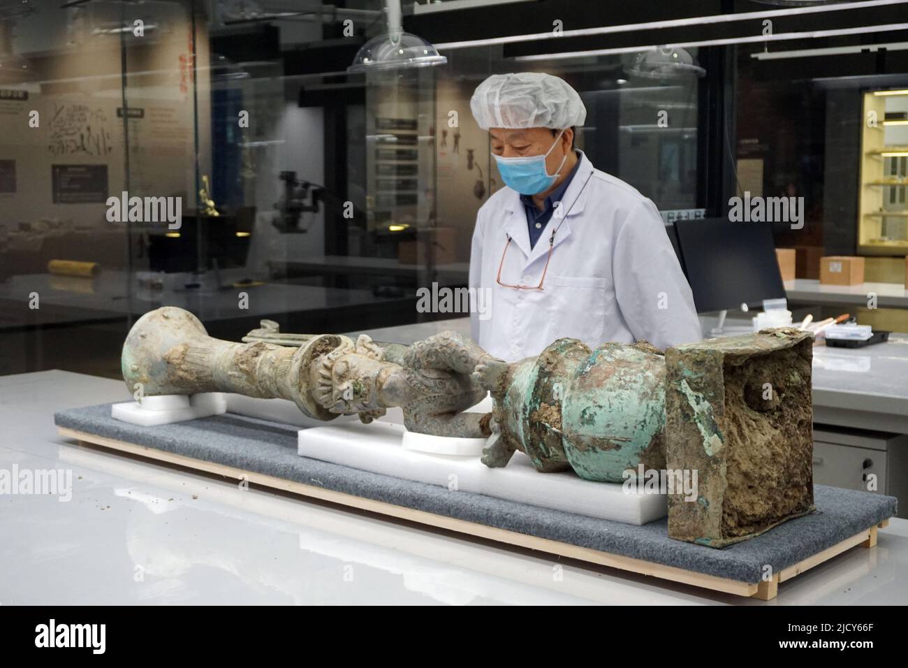 (220616) -- GUANGHAN, 16 de junio de 2022 (Xinhua) -- Lei Yu, investigador del Instituto Provincial de Investigaciones sobre Reliquias Culturales y Arqueología de Sichuan, ve una escultura de bronce que representa una figura de cabeza humana, cuerpo de serpiente y uña de pájaro el 16 de junio de 2022. Una escultura de bronce recién desenterrada en el famoso sitio de las ruinas de Sanxingdui fue igualada con éxito con otra parte de bronzware después de ser apartada hace unos 3.000 años, el equipo arqueológico confirmó el jueves. La sofisticada escultura de bronce representa una figura de una cabeza humana y cuerpo de serpiente, con ojos salientes, colmillos, a. Foto de stock