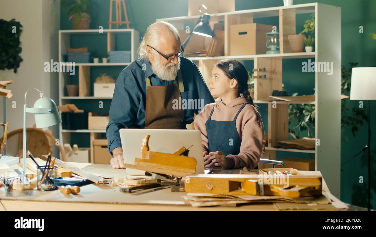 Grandpa Carpenter con nieta Teenage Modelo 3D Esketches usando un portátil Foto de stock