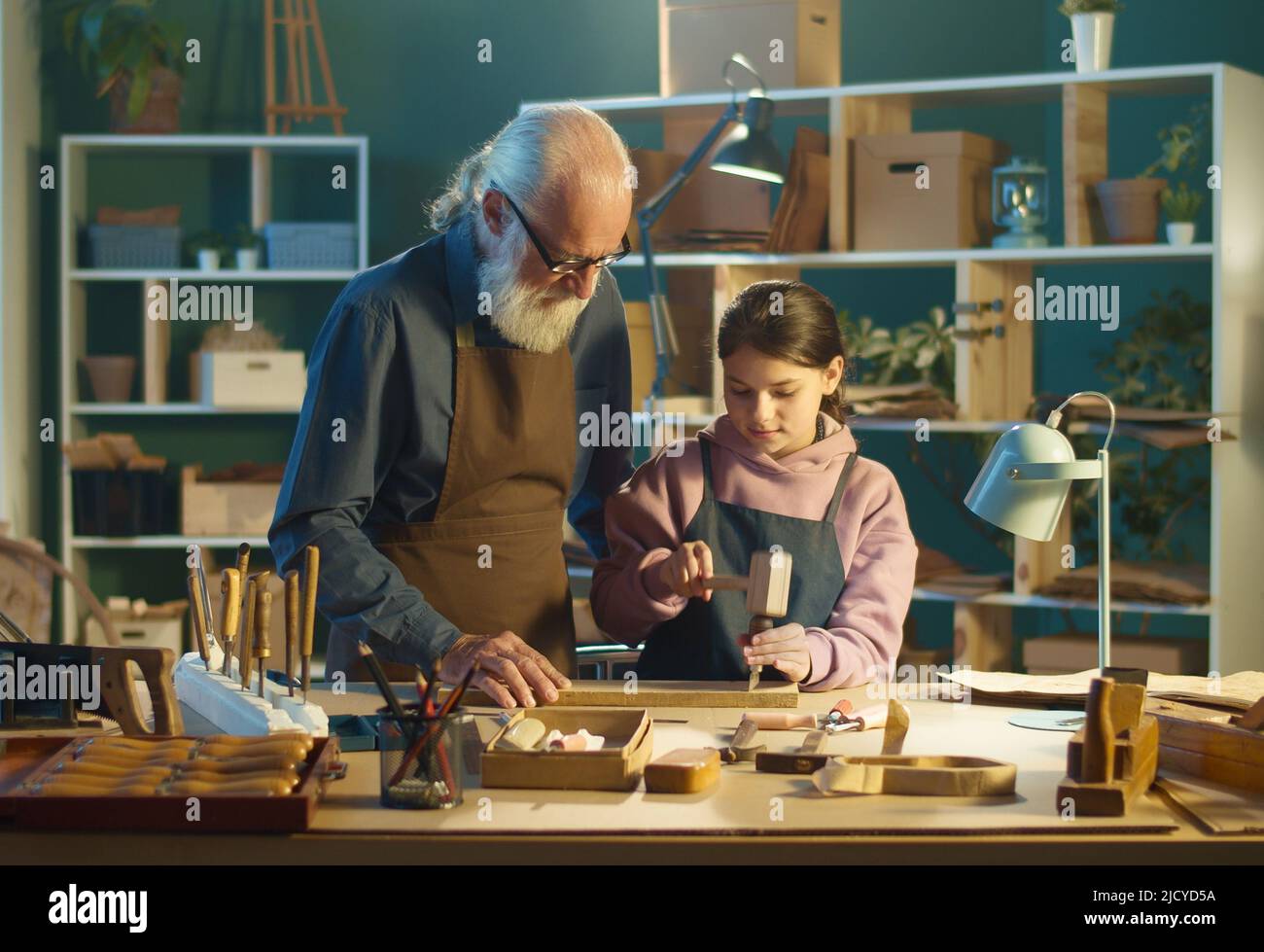 El abuelo Carpenter con su nieta adolescente trabaja en el taller Foto de stock