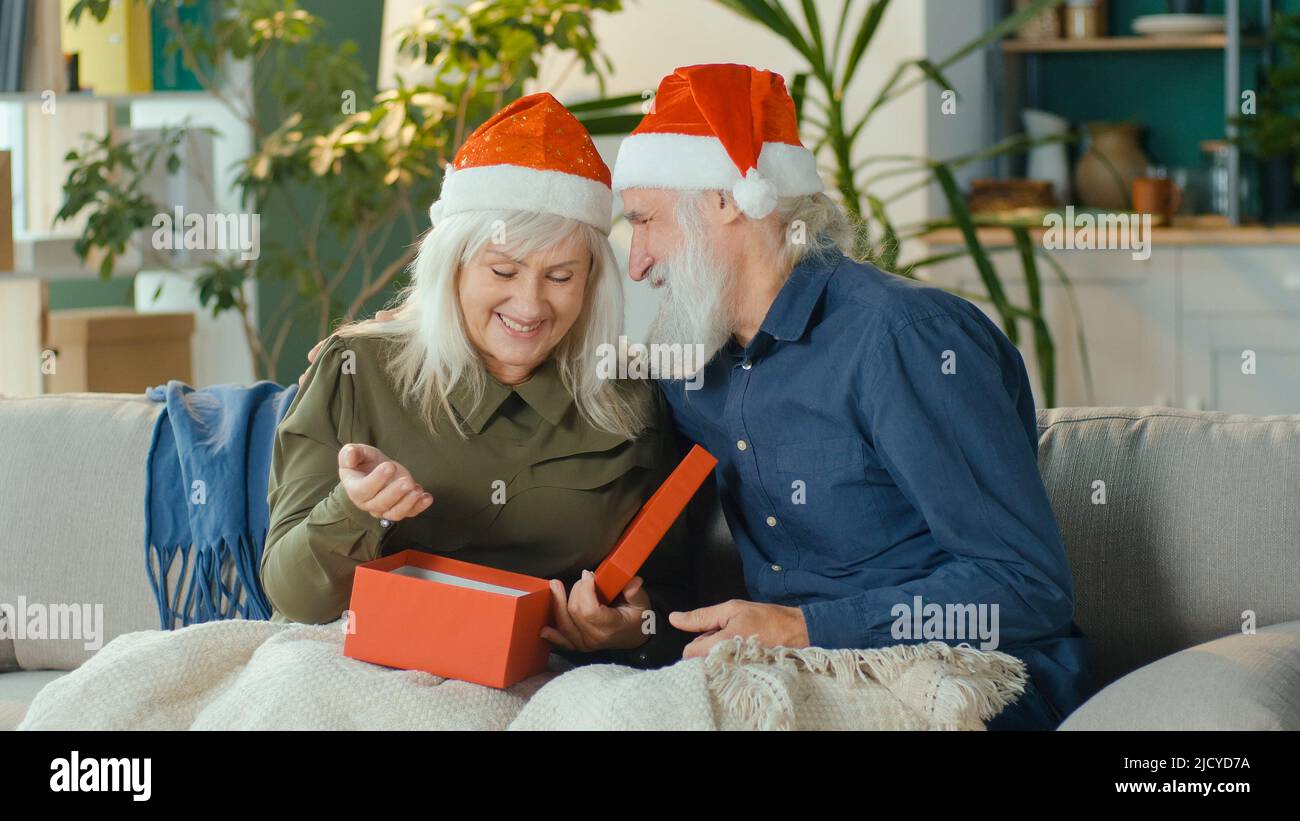 Una pareja de ancianos casados alegre celebrando la Navidad en la sala de estar Foto de stock