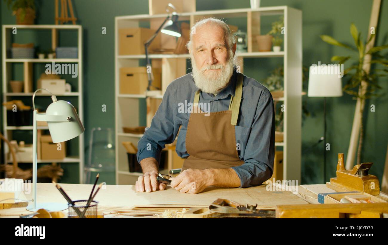 Carpintero de hombre mayor profesional trabajando en madera usando herramientas de carpintería Foto de stock