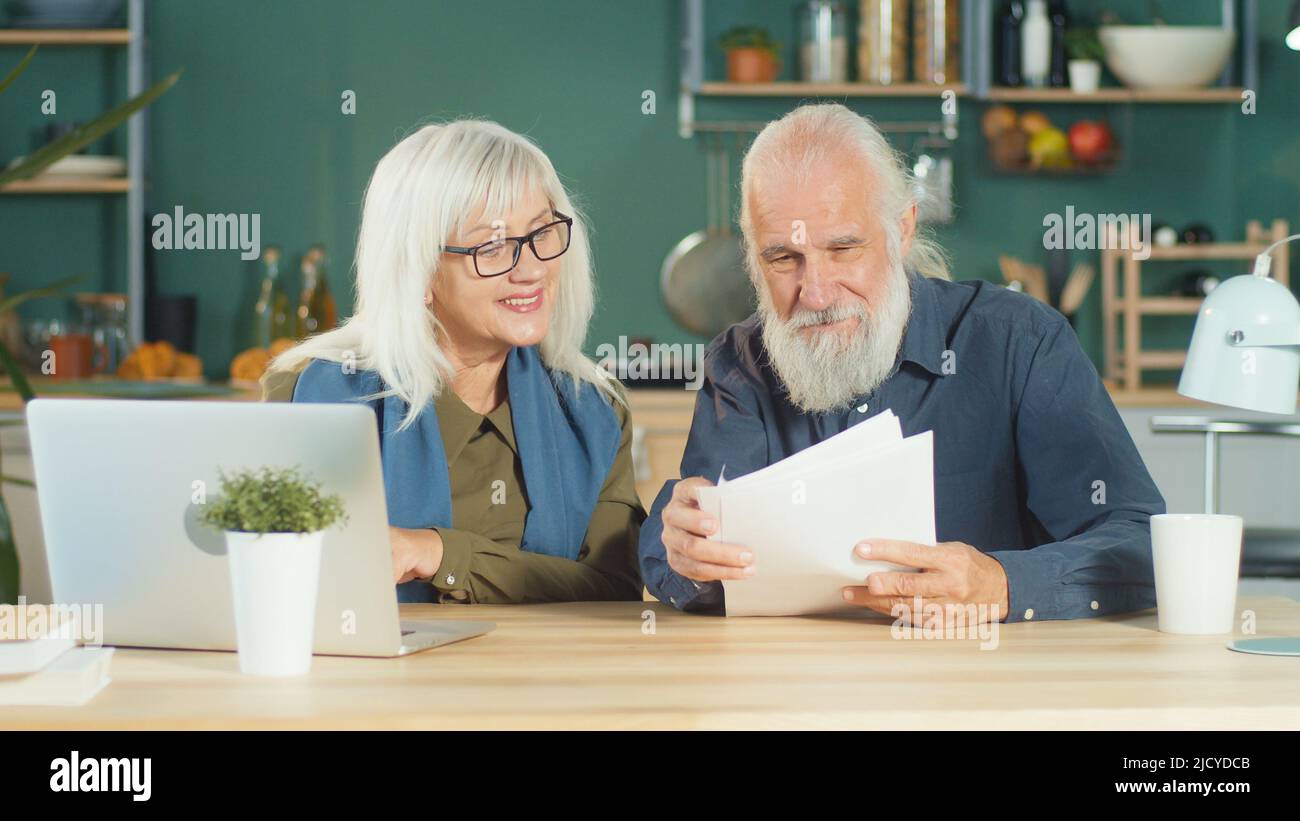 Un hombre y una mujer de edad avanzada pagan facturas y administran un presupuesto, hacen cheques contables Foto de stock
