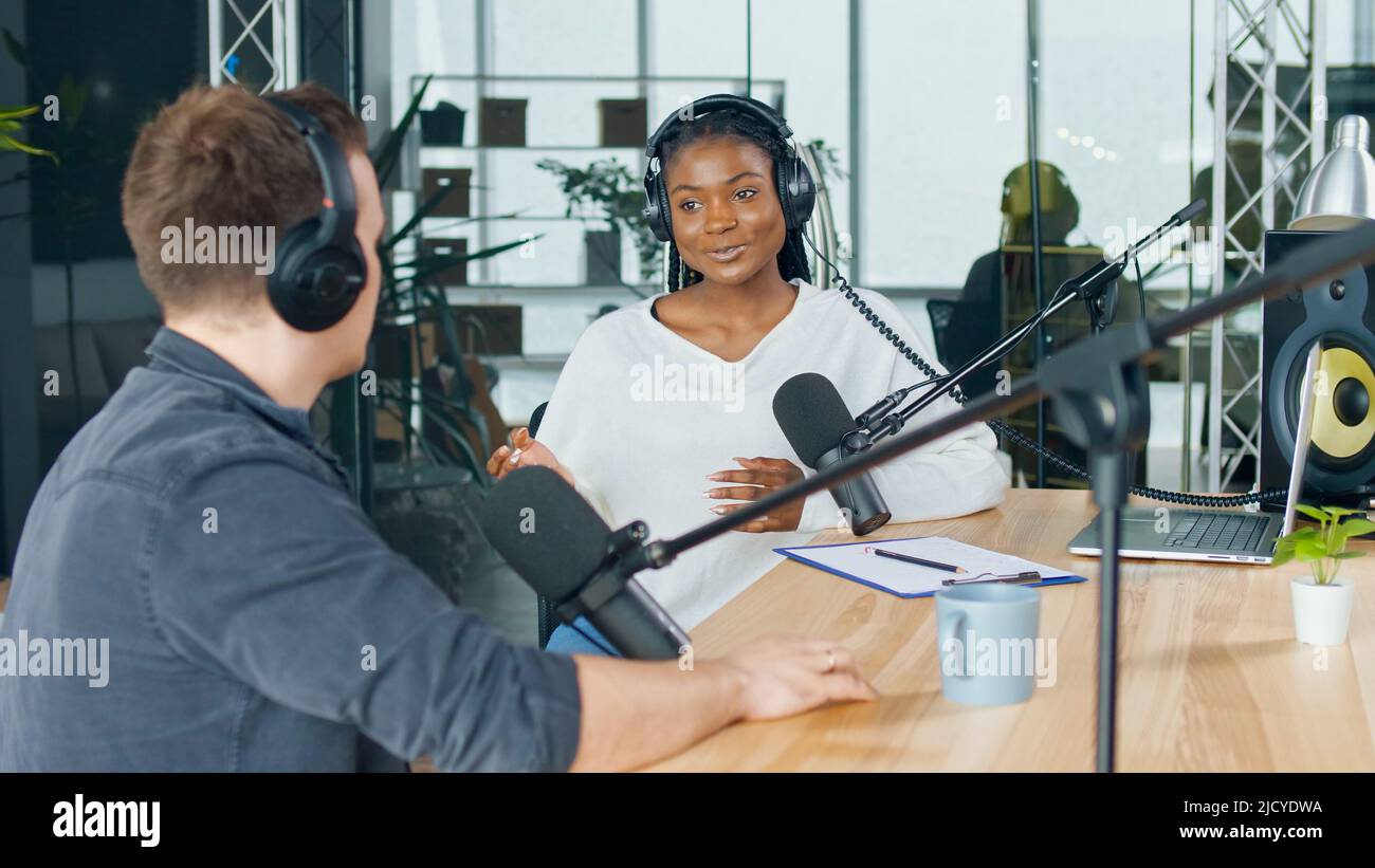 Mujer anfitriona Hablando con una amiga invitada en una emisora de radio Podcast en el estudio. Foto de stock