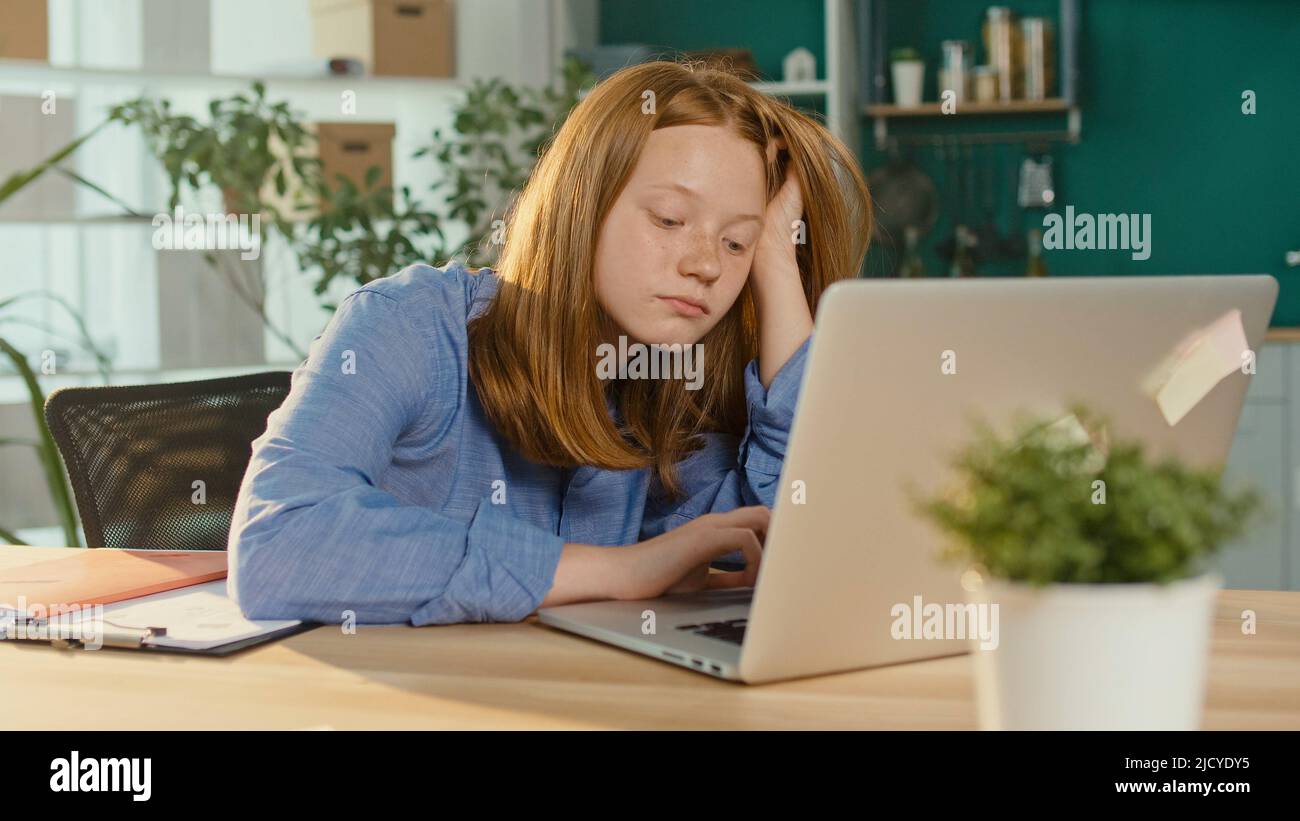 Adolescente Cansado Schoolgirl mientras estudiaba en línea en un ordenador portátil. Estudiante SAD. Foto de stock