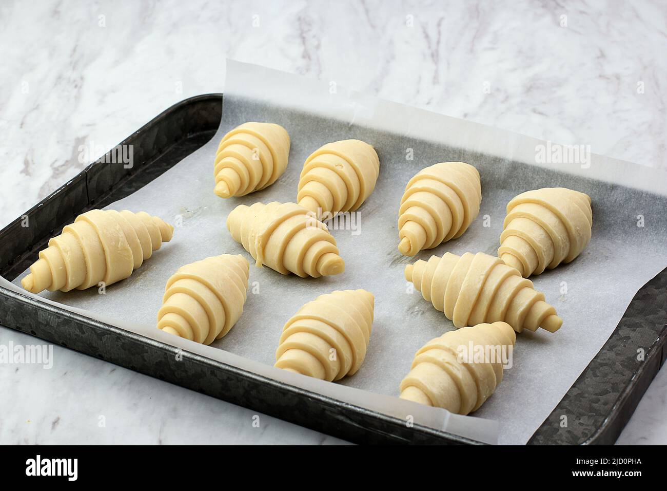 Proceso de elaboración de croissant casero, preparación de croissant crudo  de hornear en casa en rústico con forro de papel de hornear, sobre mesa de  mármol Fotografía de stock - Alamy