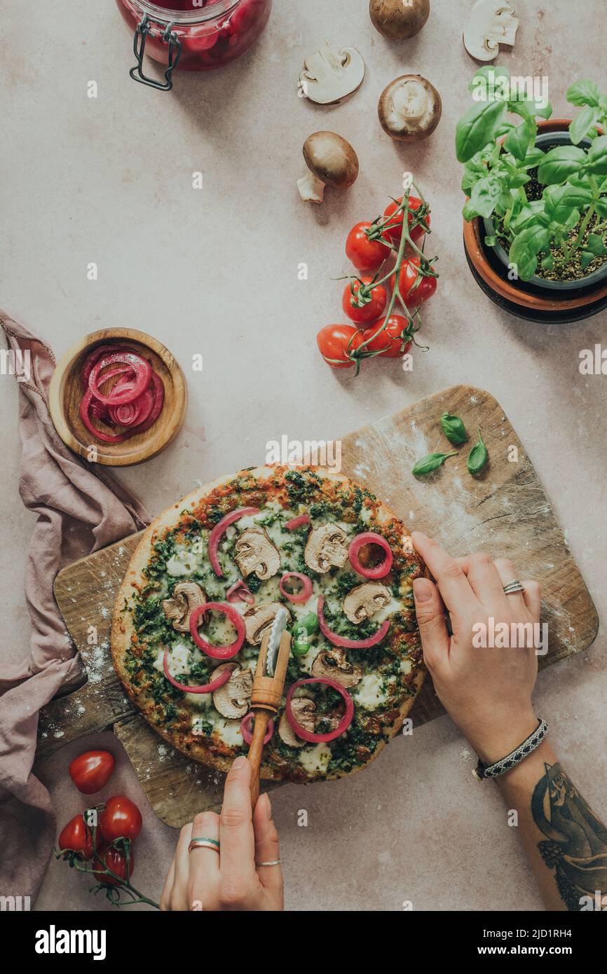 Manos cortando pizza casera Foto de stock