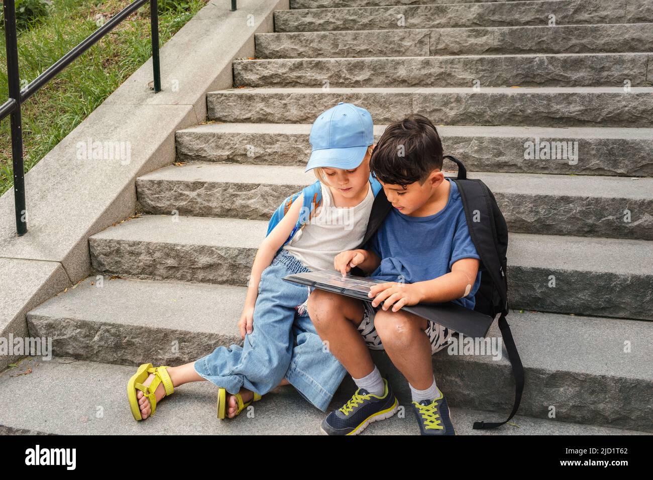 Niños sentados en las escaleras y mirando el álbum Foto de stock