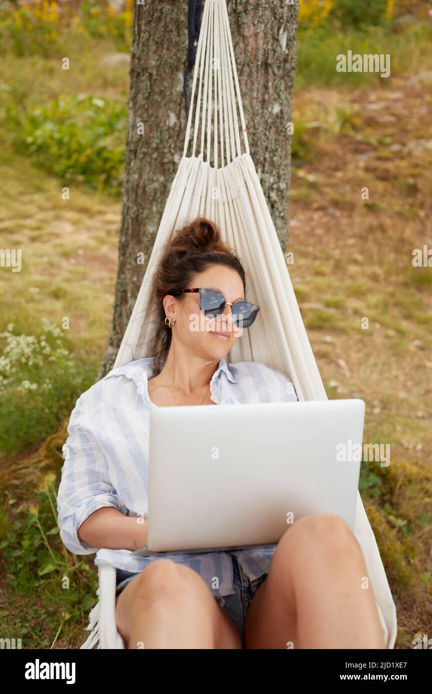 Mujer usando el portátil en la hamaca Foto de stock