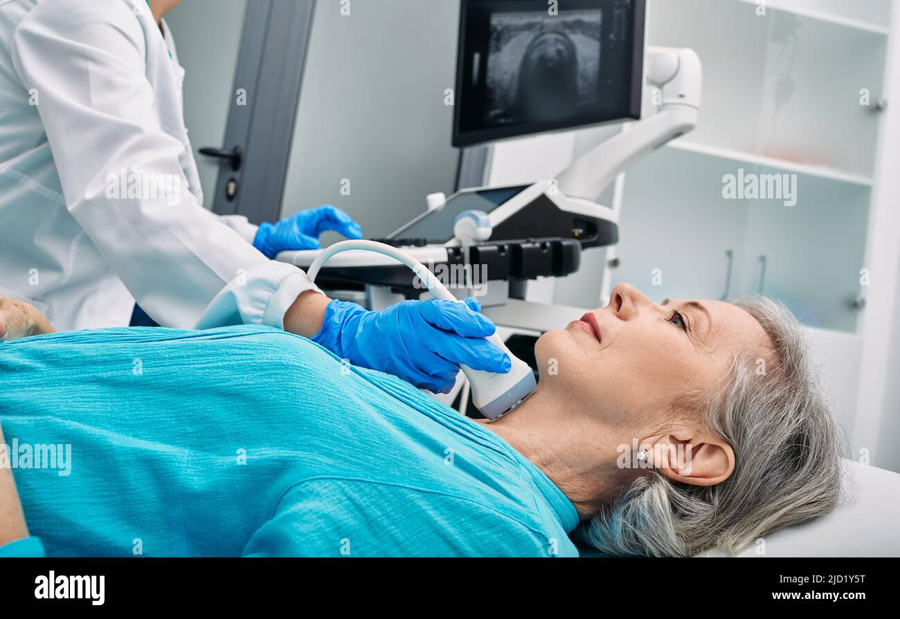 Médico que hace la ecografía a la paciente mujer mayor en la oficina de ultrasonido de la clínica médica Foto de stock