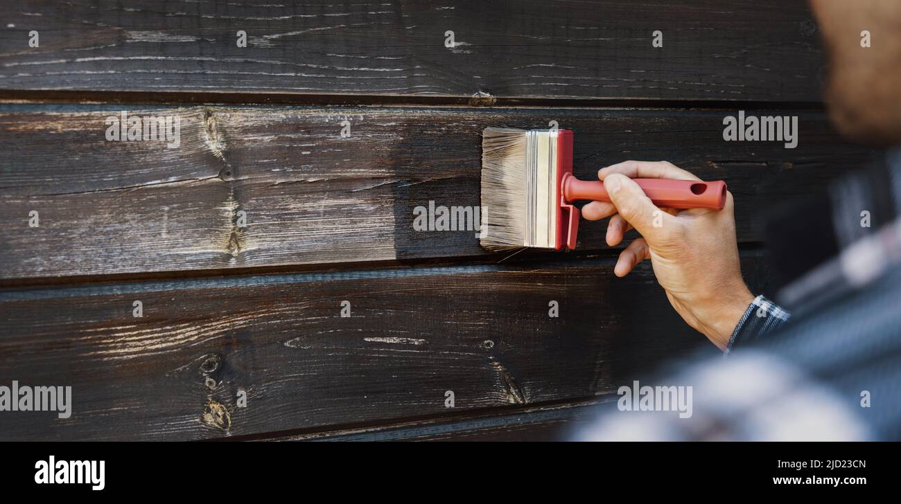 renovación de revestimientos exteriores de madera de la casa. el hombre restaura la pintura de viejos tablones de madera Foto de stock