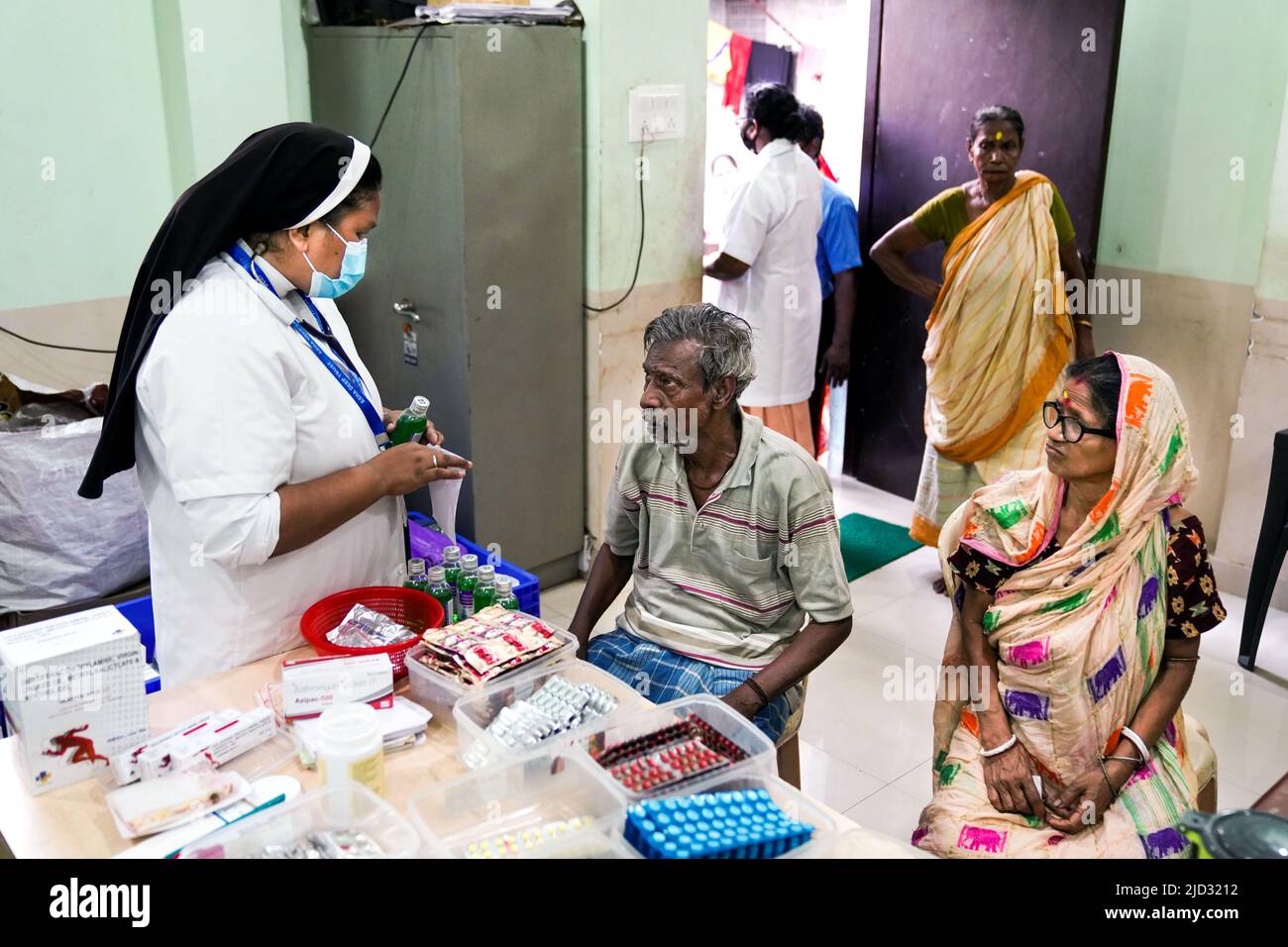 Una hermana católica asesora a personas pobres de un barrio bajo sobre cuestiones de salud en la clínica móvil de Asha Deep Trust en Kolkata, India Foto de stock