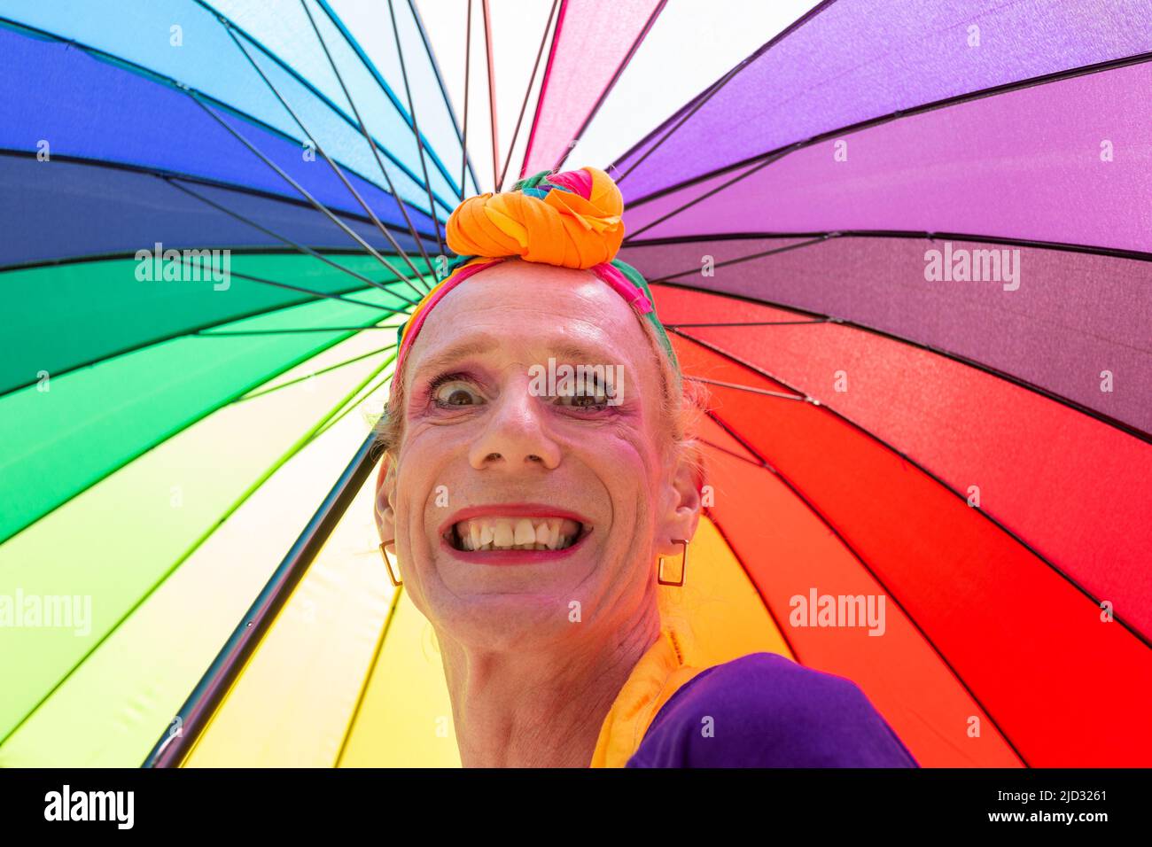 Hombre transgénero o mujer con un paraguas de arco iris brillante, Reino Unido 2022 Foto de stock